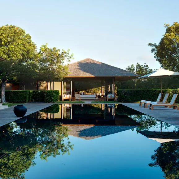 Amanyara villa with illuminated pavilion reflected in still pool at dusk, Turks & Caicos.