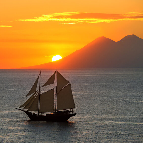 Sailing vessel at sunset off the coast of Amandira, Indonesia.
