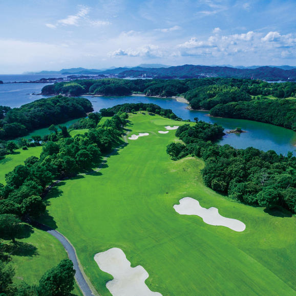 Aerial view of Amanemu's golf course with manicured fairways, bunkers, and forested edges overlooking coastal waters and islands.