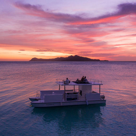 Floating platform at sunset with island silhouette at Amanpulo.