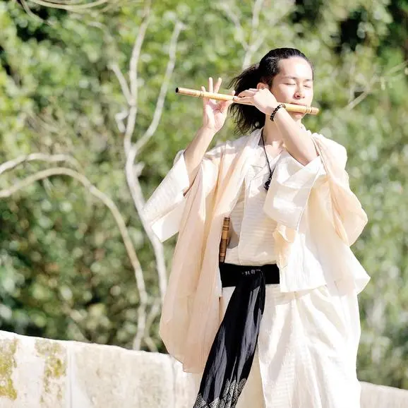 Musician playing shinobue flute in autumn garden at Aman Kyoto.
