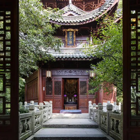 法云安缦度假村的传统寺庙建筑，红木门框两侧爬满绿色植物，庭院宁静悠远。