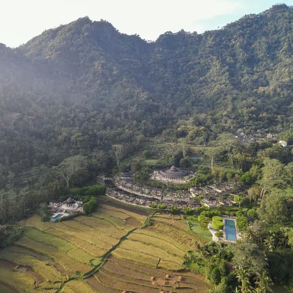 Aerial view of Amanjiwo nestled among terraced rice paddies and volcanic peaks in Java, Indonesia.