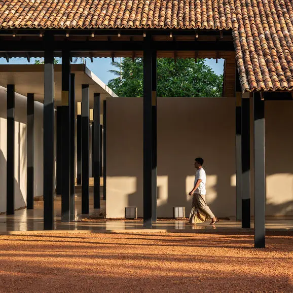 Amanwella resort exterior with terracotta roof and open-air pavilion casting shadows on the ground.