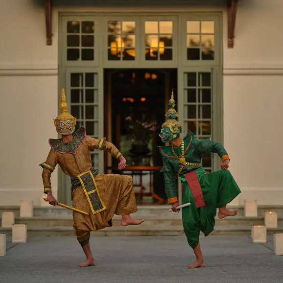 Lao masked dancers perform traditional drama at Amantaka's poolside dining venue during evening entertainment.