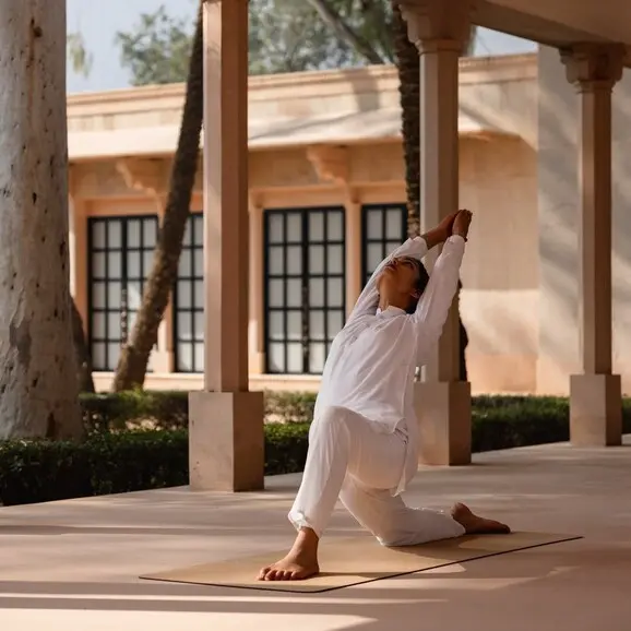 Woman practising yoga beneath the colonnade at Amanbagh's poolside.