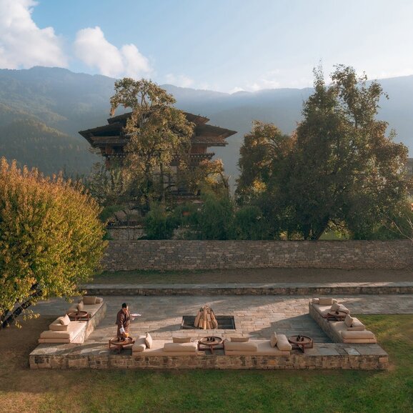 Firepit seating area at Amankora's Bumthang Lodge, surrounded by forested valleys in Bhutan.