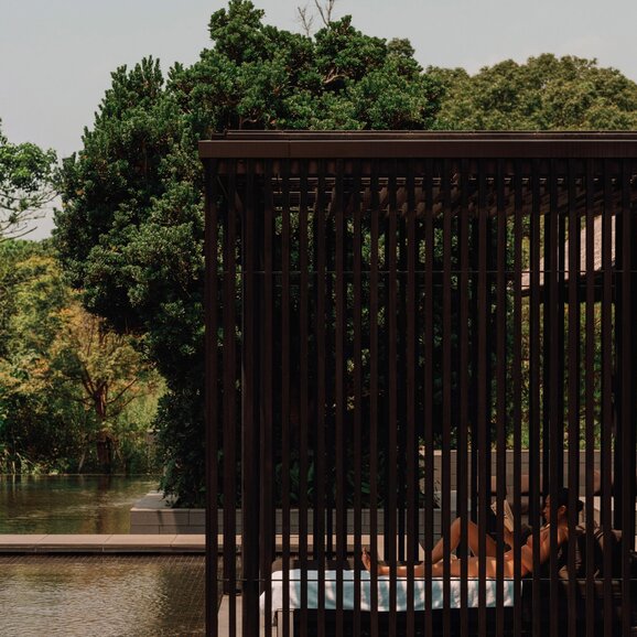 Wooden bathing pavilion at Amanemu with thermal spring waters and verdant surroundings.