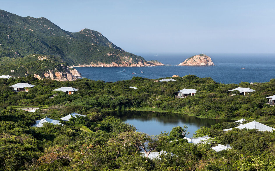 アマノイ リゾートの湖畔パビリオンから、緑に囲まれた池と遠くの海岸線を望む。