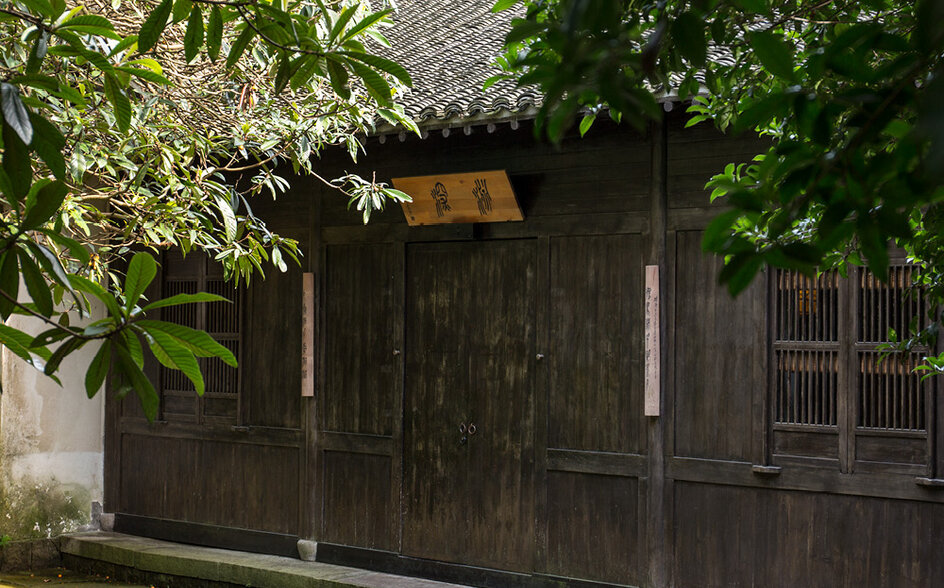 Village room at Amanfayun with dark wooden exterior and lush greenery.