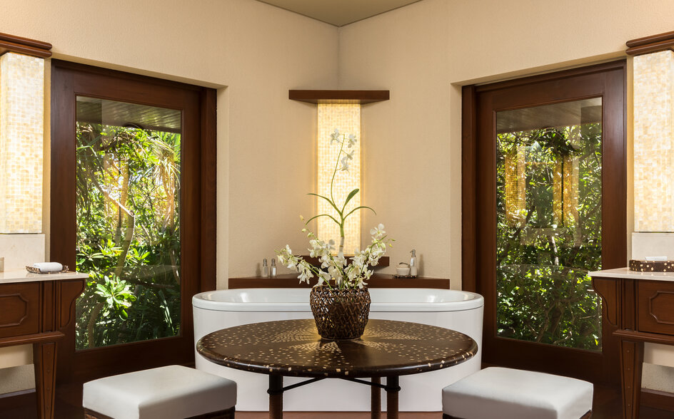 Hillside casita bathroom at Amanpulo with dual vanities, round mirror and natural light from windows.