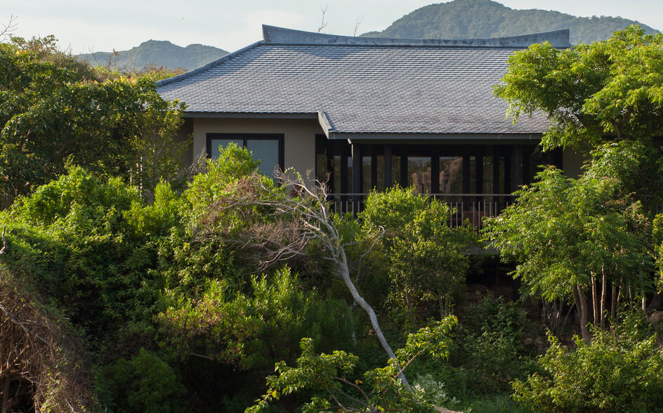 アマノイのリゾートにある湖上の建築物。緑に囲まれた水辺に建つ、瓦葺き屋根の建物。