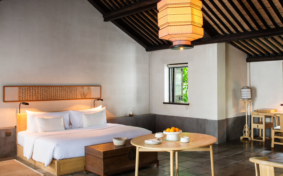 Bedroom at Amanfayun with slatted timber ceiling, pendant lantern, and minimalist furnishings.