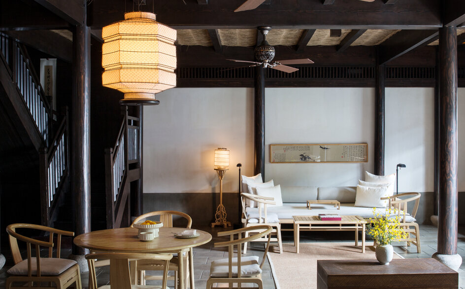 Amanfayun villa living space with wooden beams, pendant lighting, and contemporary furnishings overlooking the landscape.