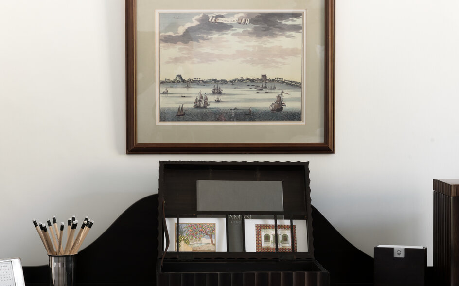 Framed landscape artwork above a black desk with decorative objects at Amangalla.