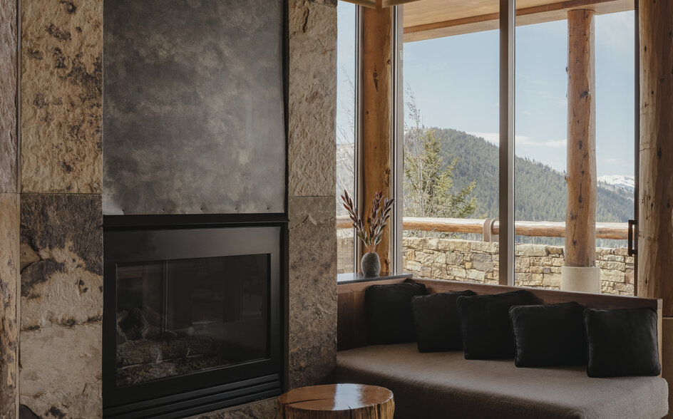 Fireplace with stone surround and window seat overlooking mountains at Amangani.
