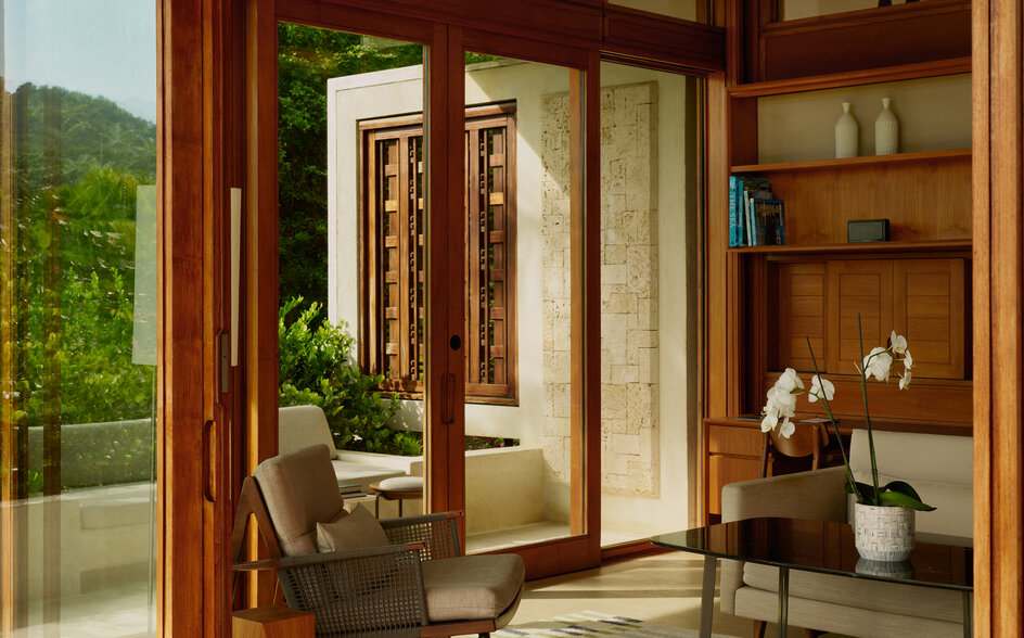 Salon lumineux avec baies vitrées, mobilier en bois et vue sur la verdure, Amanera Resort.