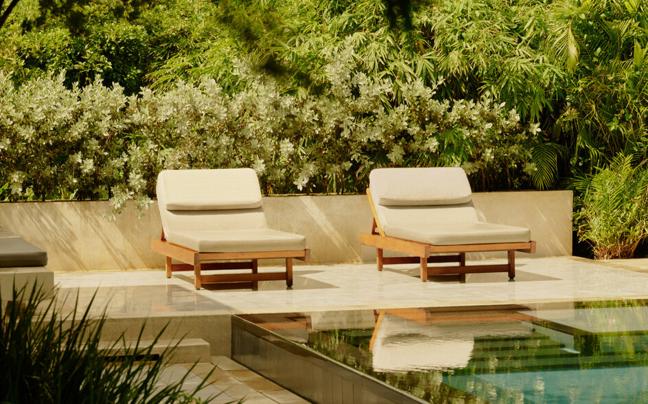 Deux chaises longues blanches face à une piscine aux eaux calmes à Amanera, resort en République dominicaine.