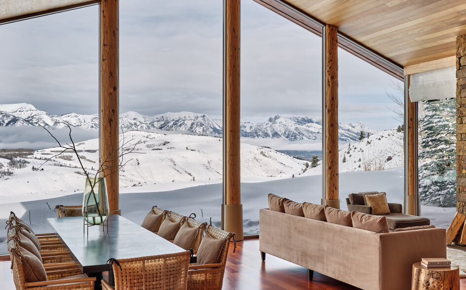 Amangani home interior with floor-to-ceiling windows overlooking snow-capped mountains and valley below.