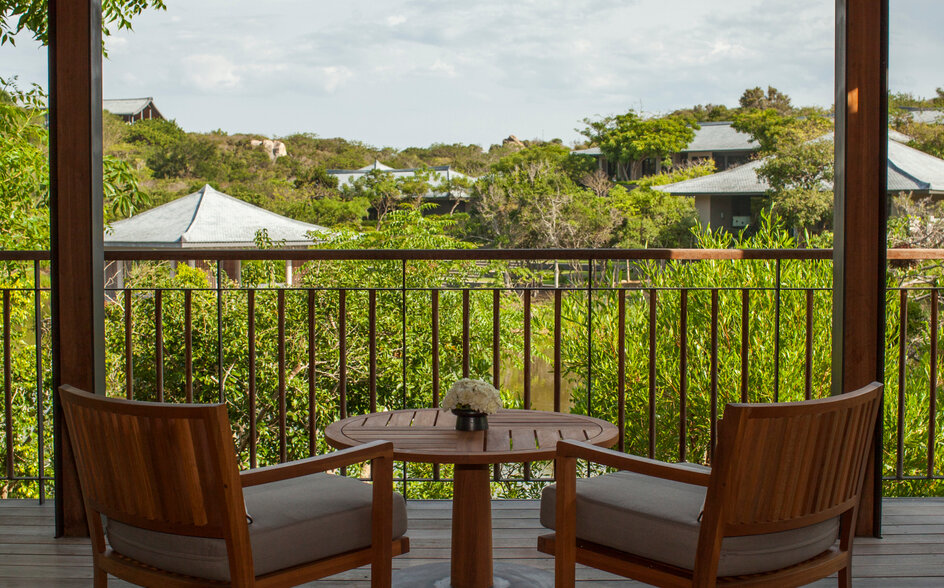 アマノイ リゾートのレイク パビリオン テラスから、緑の景観を望む2脚の椅子と小卓。