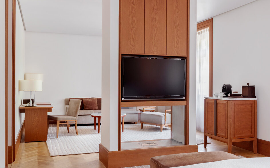 Garden view room at Aman Sveti Stefan with warm wood furnishings and television integrated into wooden cabinetry.