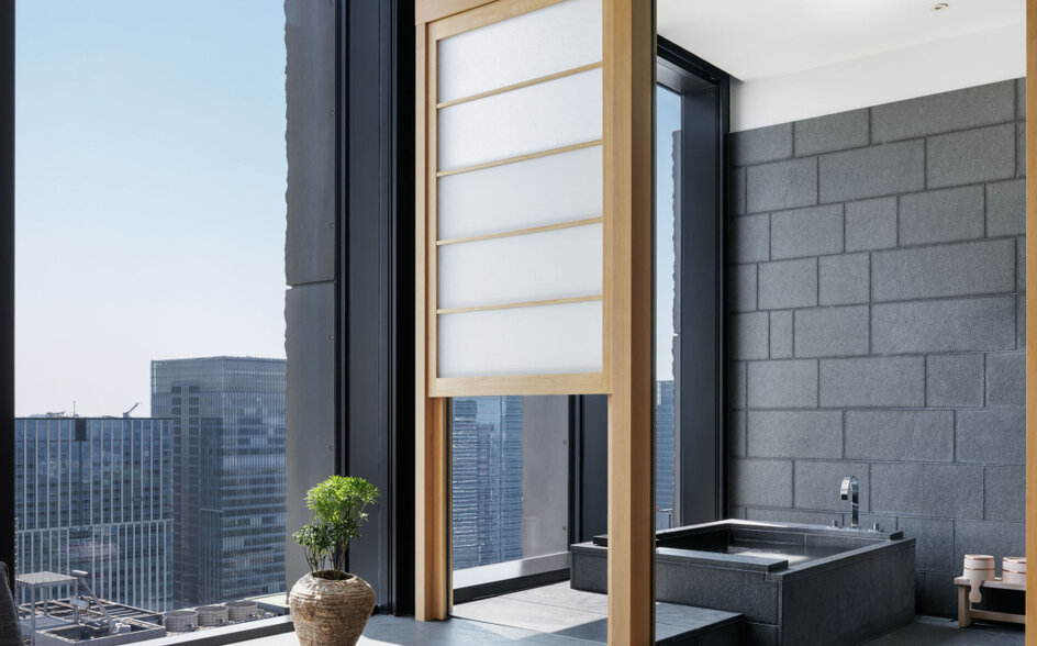 Bathroom at Aman Tokyo with grey subway tiles, wooden frames, and floor-to-ceiling windows overlooking the city skyline.