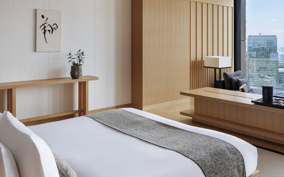 Tokyo Suite bedroom at Aman Tokyo with wooden furnishings and city views from floor-to-ceiling windows.