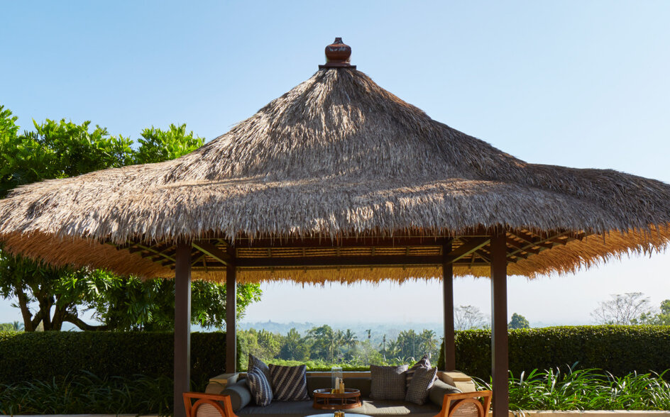 安缦齐和度假村花园套房的露台，配有茅草凉亭和木制座椅，俯瞰周围景观。