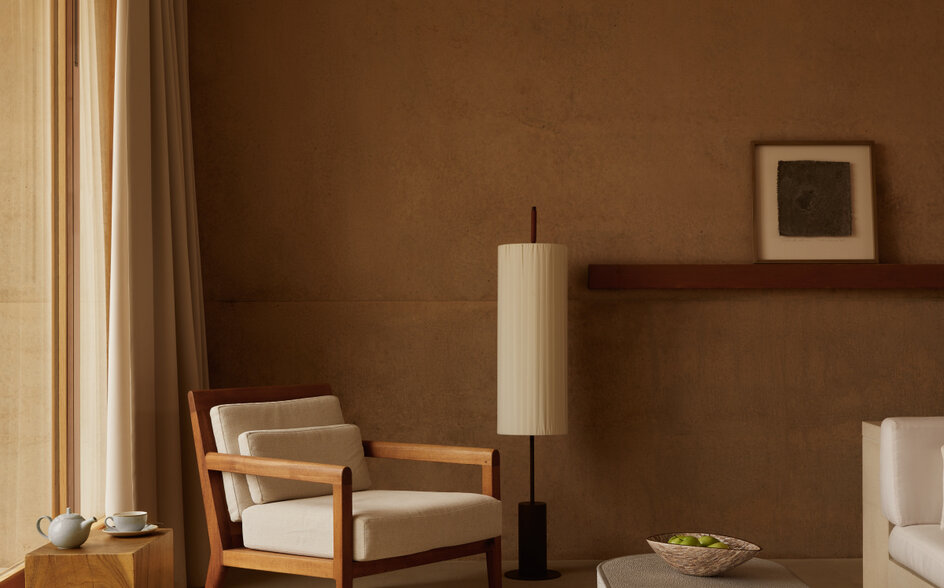 Desert Suite at Amangiri, with warm terracotta walls, wooden chair, and minimal furnishings bathed in natural light.