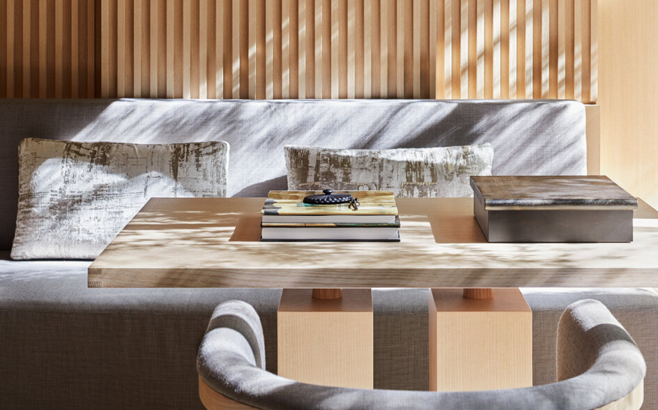 Aman Kyoto accommodation with striped wooden headboard, layered bedding, and sculptural wooden stool in foreground.
