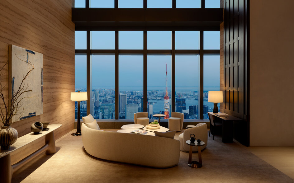 Communal library at Aman Tokyo with curved seating, floor-to-ceiling windows overlooking the city at dusk.