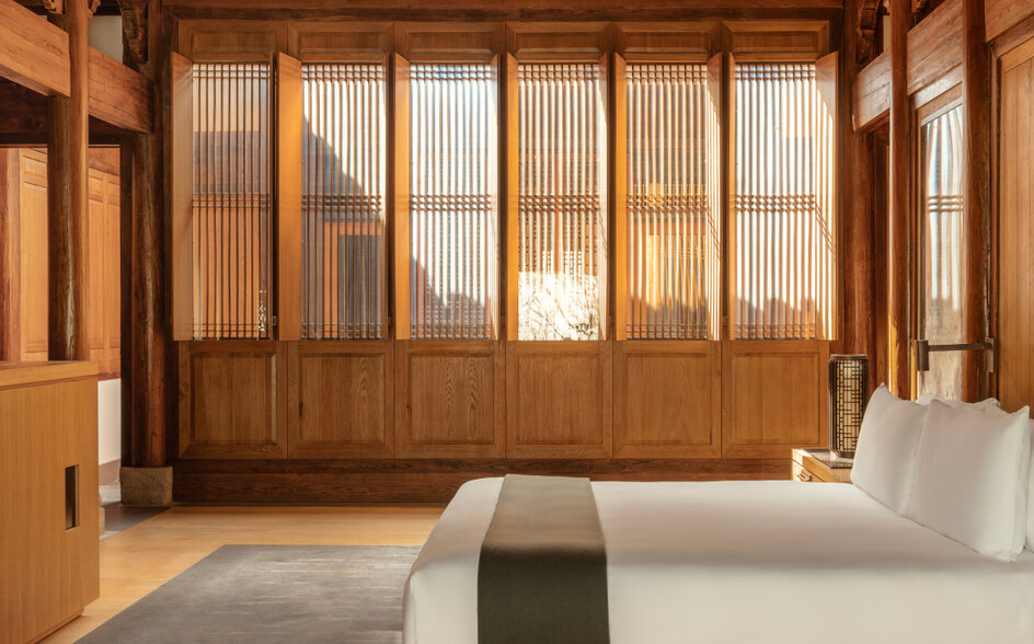 Minimalist villa bedroom at Amanyangyun with wooden architectural details and floor-to-ceiling windows overlooking gardens.