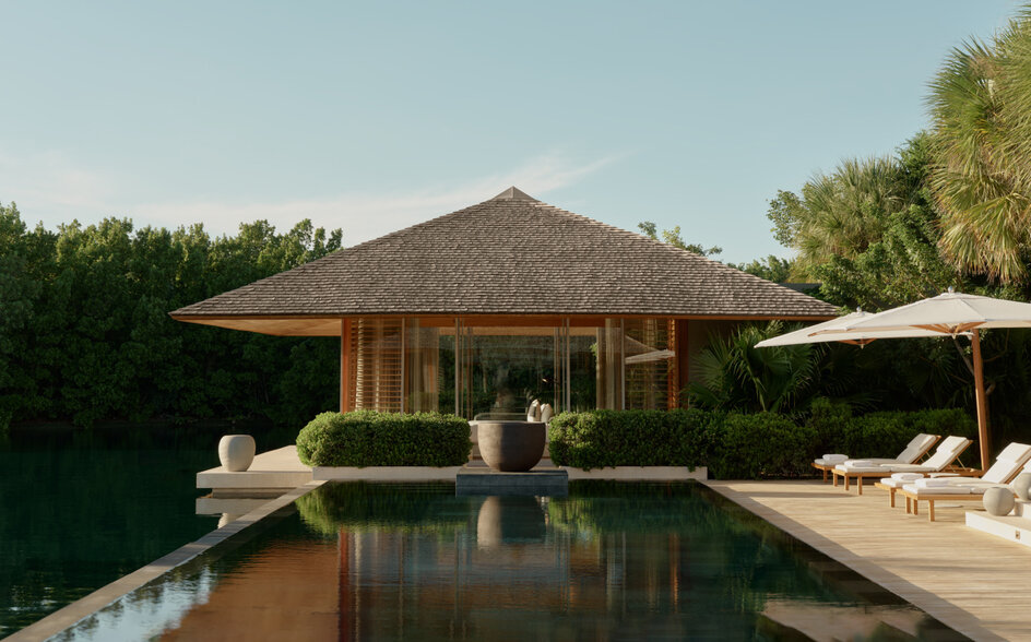 Four-bedroom villa at Amanyara with thatched roof, reflecting pool and shaded lounging areas.
