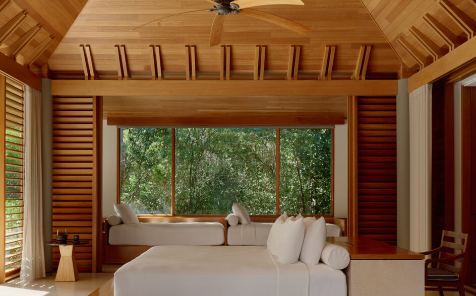 Principal bedroom in a three-bedroom villa at Amanyara, with wooden ceiling, louvred walls and views to tropical greenery.