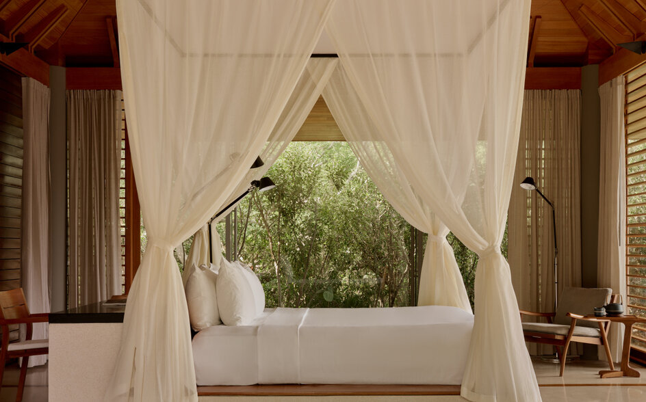 アマンヤラのトランクイリティ・パビリオンの寝室。白いカーテンに囲まれたベッドから緑の庭園が見える。