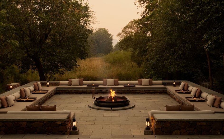 Fire pit seating area at Aman-i-Khas, India, at dusk with stone benches arranged in a circle.