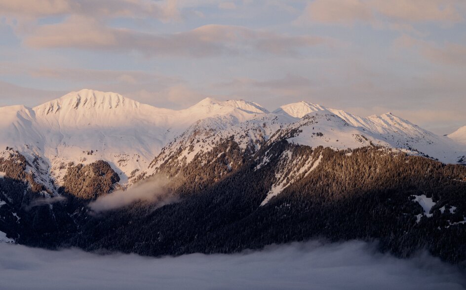 Snow-covered Alpine peaks rising above morning mist at Aman Le Mélézin, France.