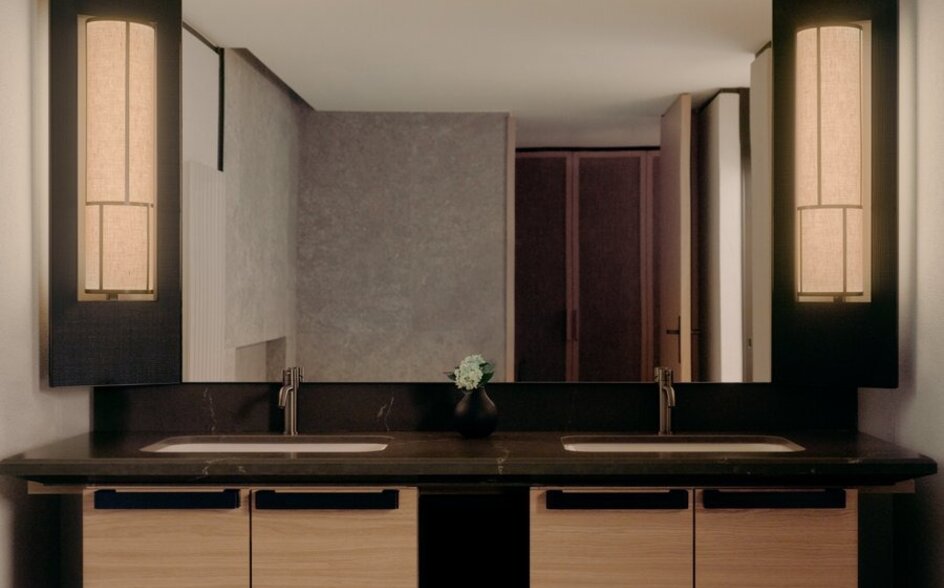 Superior room bathroom at Aman Rosa Alpina with dual vanity, illuminated mirrors and natural wood cabinetry.
