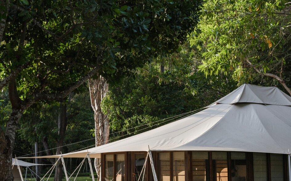 Jungle tent accommodation at Amanwana with candlelit exterior seating amongst trees at dusk.