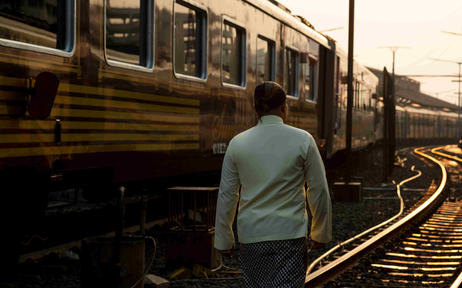 安缦齐和度假村的火车旅程，旅客站在铁轨旁观看列车。