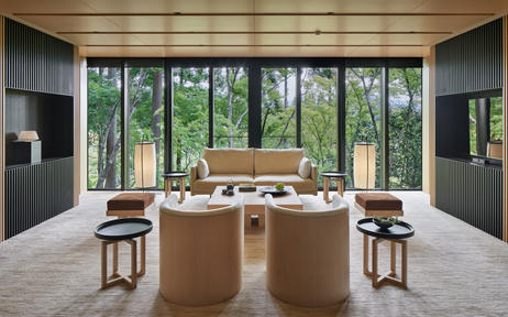 Aman Kyoto Suite with large windows overlooking garden, wooden desk, and minimalist furnishings.