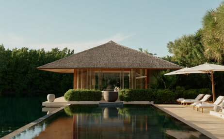 Four-bedroom villa at Amanyara with thatched roof, reflecting pool and shaded lounging areas.