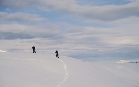 Two people snowshoeing across snowy Alpine terrain at Aman Le Mélézin, France.