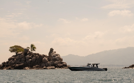 Traditional wooden boat near rocky island off the coast of Amanpuri, Thailand.
