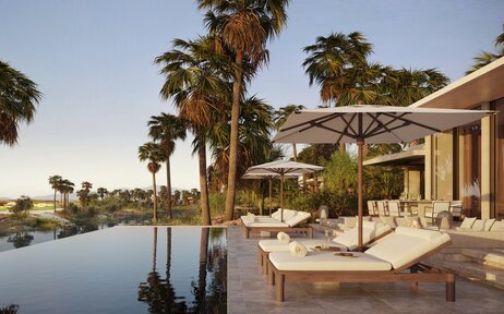Golf villa at Amanvari with terrace overlooking tranquil water and palm trees.