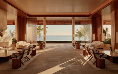 Amanvari arrival lounge with floor-to-ceiling windows overlooking Mexican landscape, warm wooden interiors and contemporary seating.