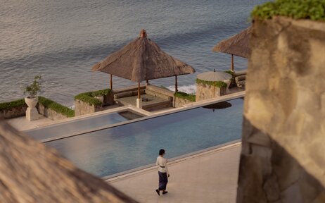 Clifftop pool overlooking the ocean at Amankila, Indonesia, with traditional wooden pavilion and stone terracing.