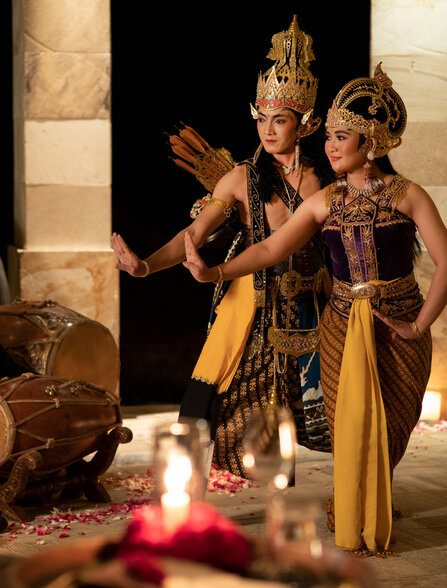 Wooden puppets in traditional Javanese dress displayed at Amanjiwo, with candlelight in the foreground.