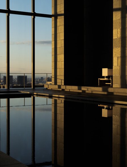Serene spa pool at Aman Tokyo reflecting the city skyline at dusk through floor-to-ceiling windows.