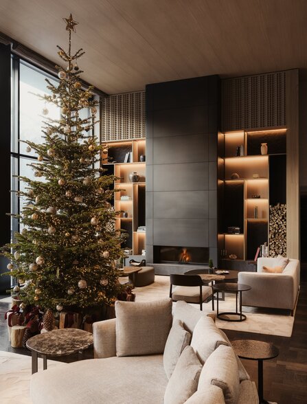 Festive seating area at Aman Rosa Alpina with decorated Christmas tree and warm lighting.